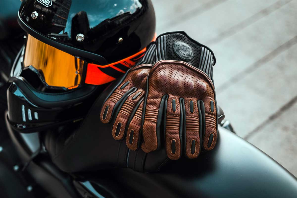 Arguably the most important part of your riding gear after your helmet is your gloves. Protecting your precious digits means wearing purpose-made motorcycle gloves and, like helmets, there’s a vast selection to choose from. If you’re looking to buy a pair of riding gloves you’ll have to decide between multiple lengths, different materials, the amount of armour you want and what riding season/s you would like the gloves to be suited to. In 2020 we saw some impressive gloves hit the market along with a few updates to models we already love. To help you fast track your glove selection process here’s our 10 best cafe racer gloves of 2020 list. ROCR X Goldtop England Predator Gloves