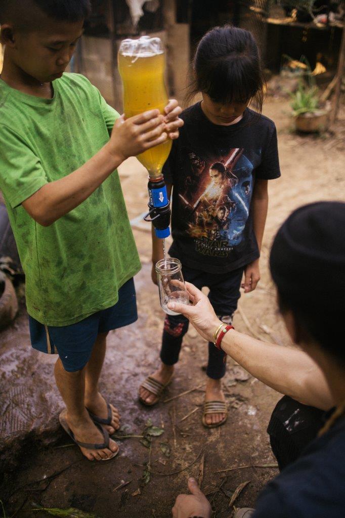 David Chang in Cambodia helping two young children filter dirty water into clean drinking water