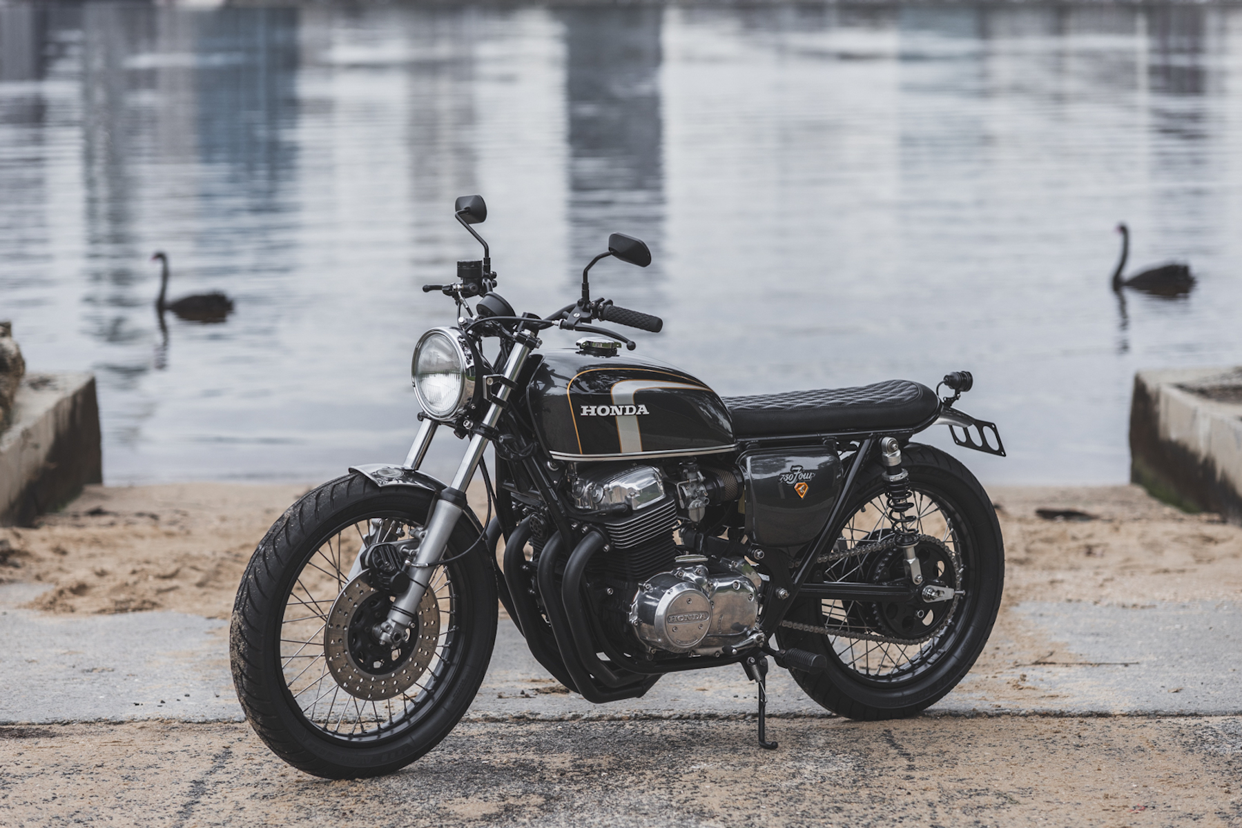 A side view of a Honda CB750 with Swans in the backround
