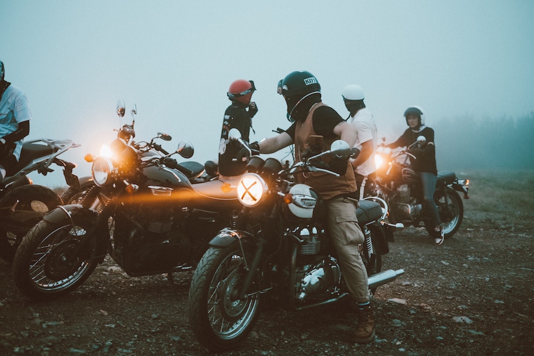 a group of motorcycle riders gather on a foggy morning