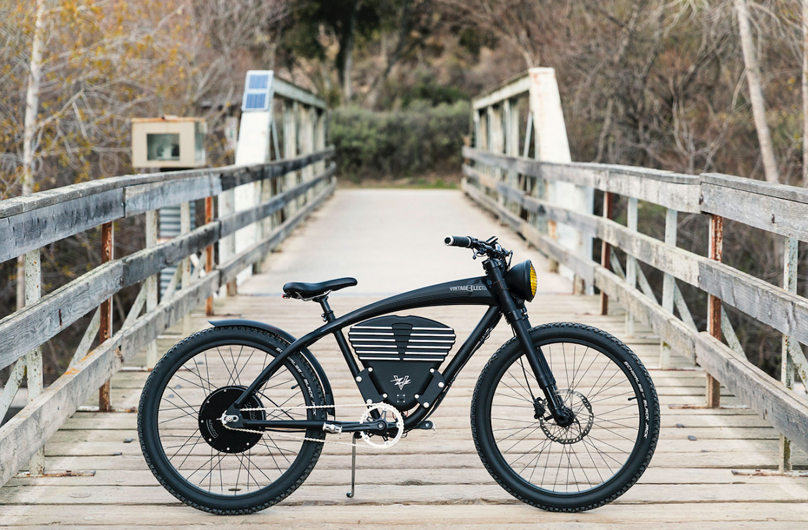 Black vintage-style eBike on bridge in forest