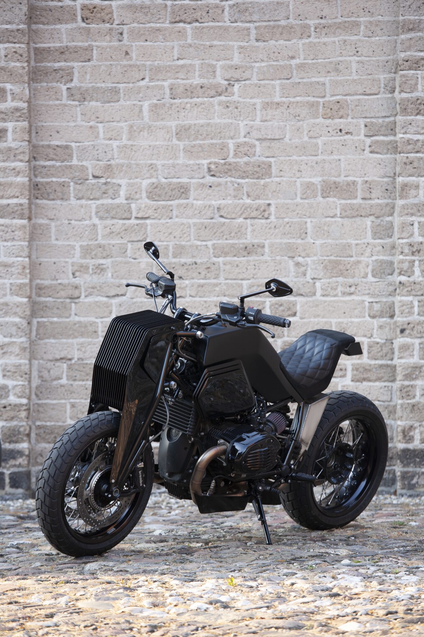 Moto Adonis BMW R nineT Girder custom motorcycle in front of brick wall