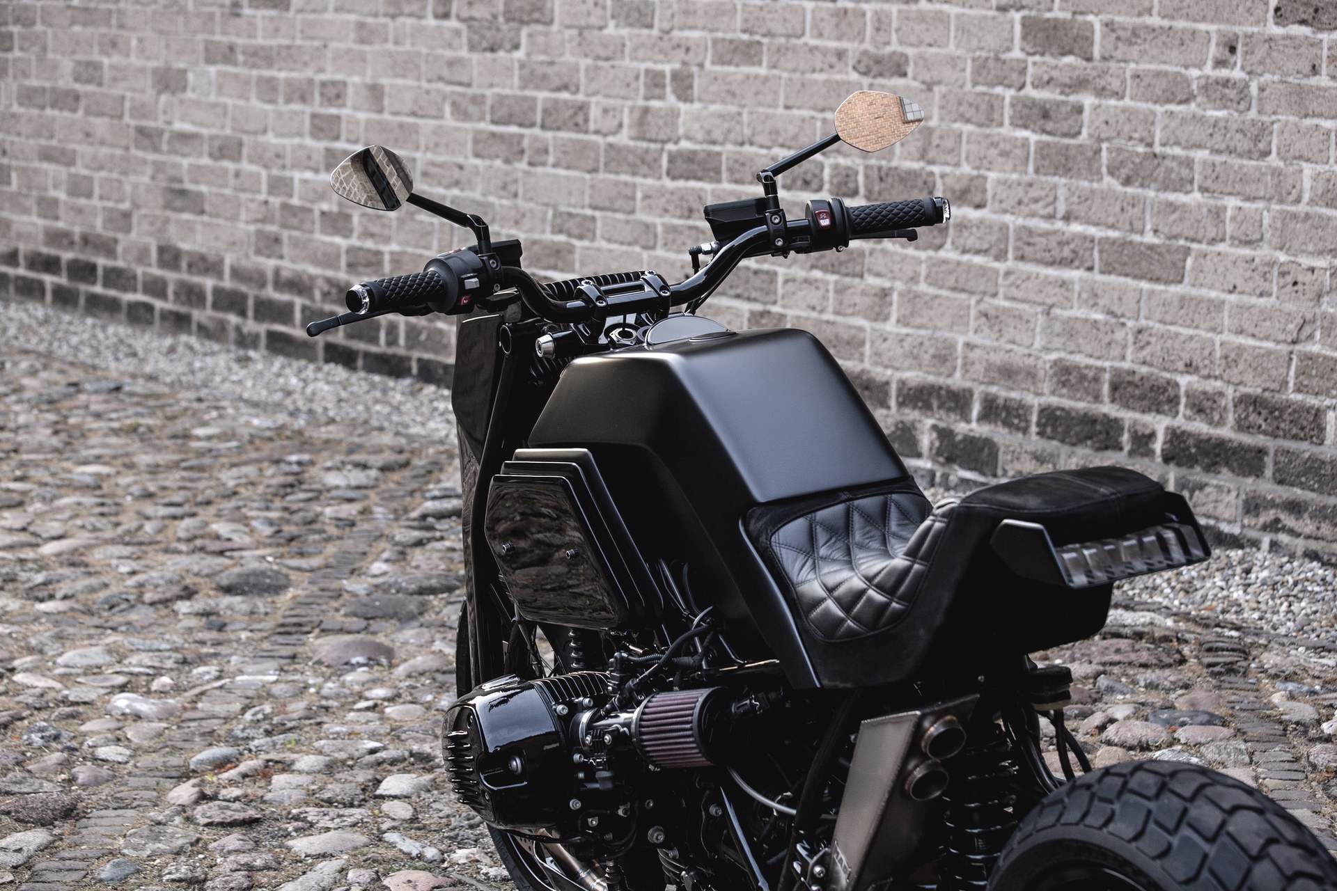 Black BMW R nineT Girder custom bike by Moto Adonis in front of brick wall