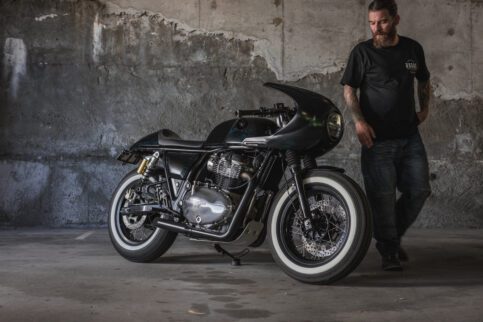 A side view of a Royal Enfield Continental GT 650 cafe racer with a man in a car park