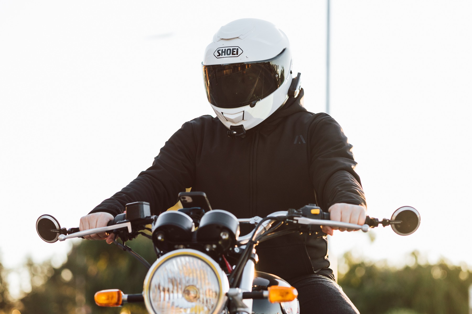 Portrait photo of a person sitting on a motorcycle wearing an Akin Moto Hurricane Hoodie