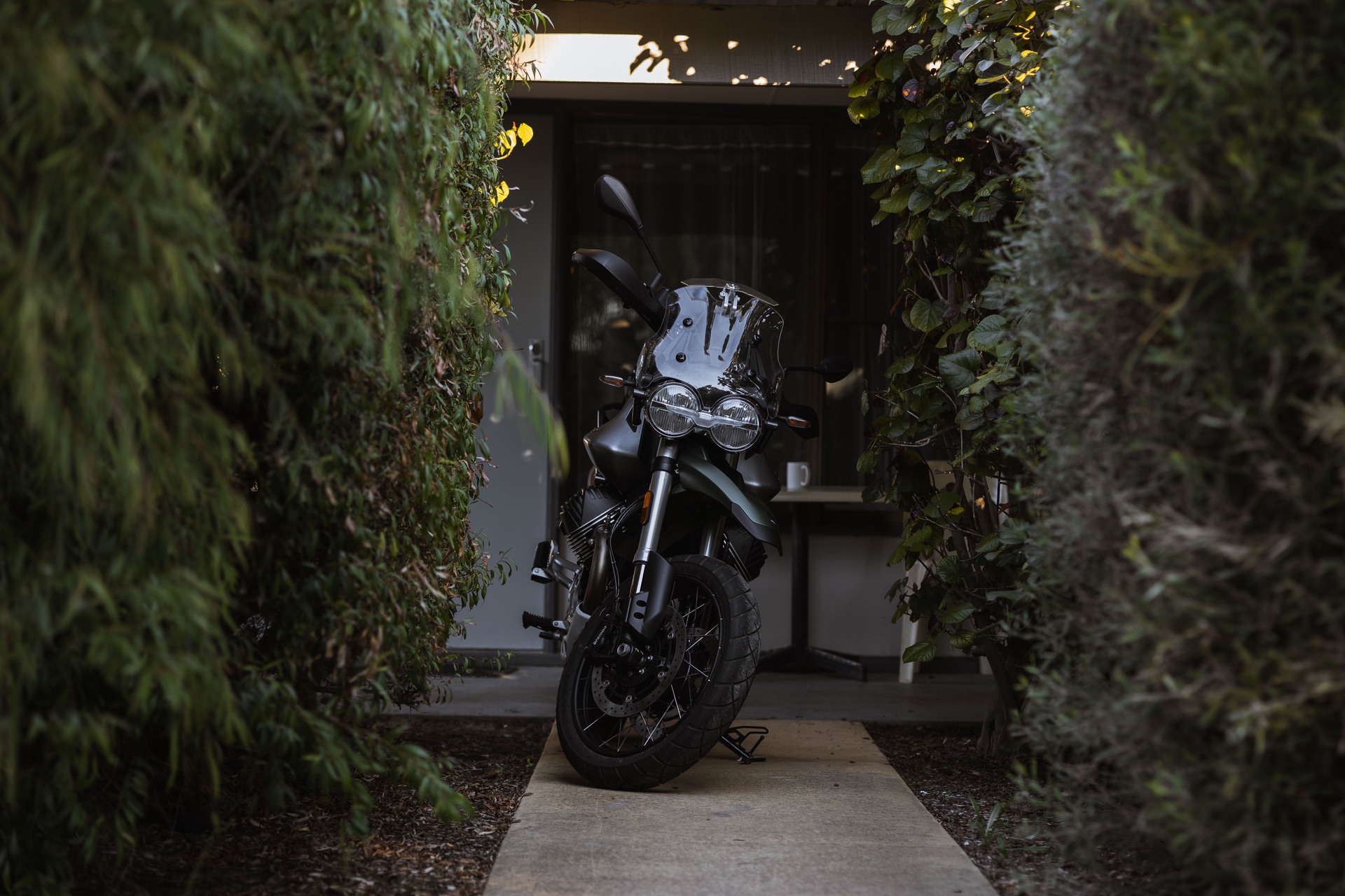 Moto Guzzi V85TT parked outside house