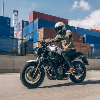A 2020 Yamaha XSR700 motorcycle rides along a cargo container terminal