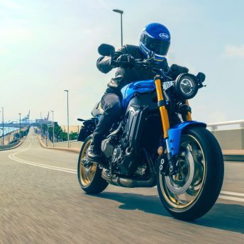 The 2022 Yamaha XSR900 motorcycle - front 3/4 profile as it rides under an overpass