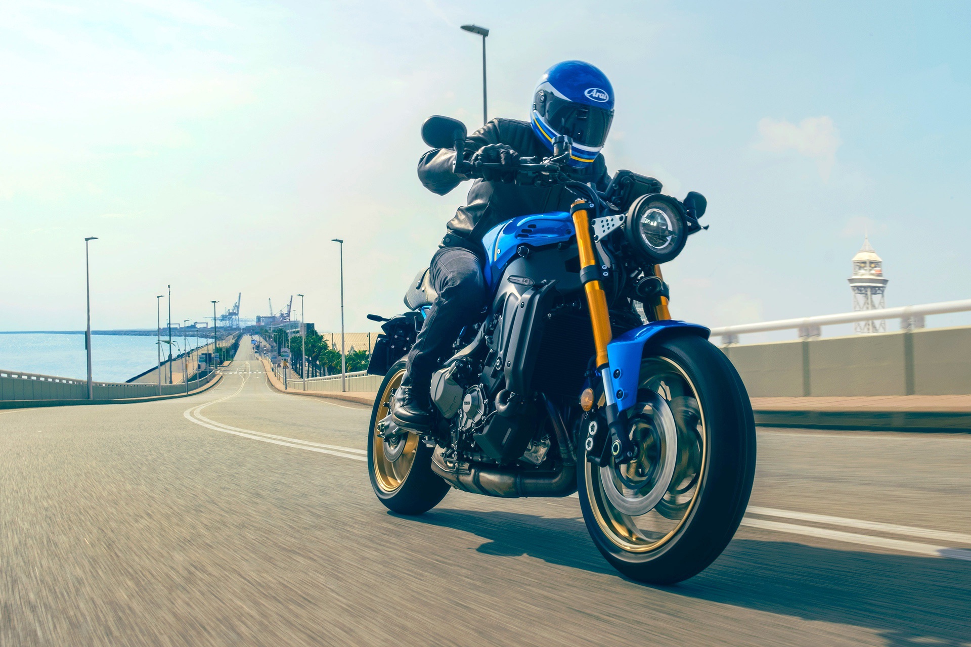 The 2022 Yamaha XSR900 motorcycle - front 3/4 profile as it rides under an overpass