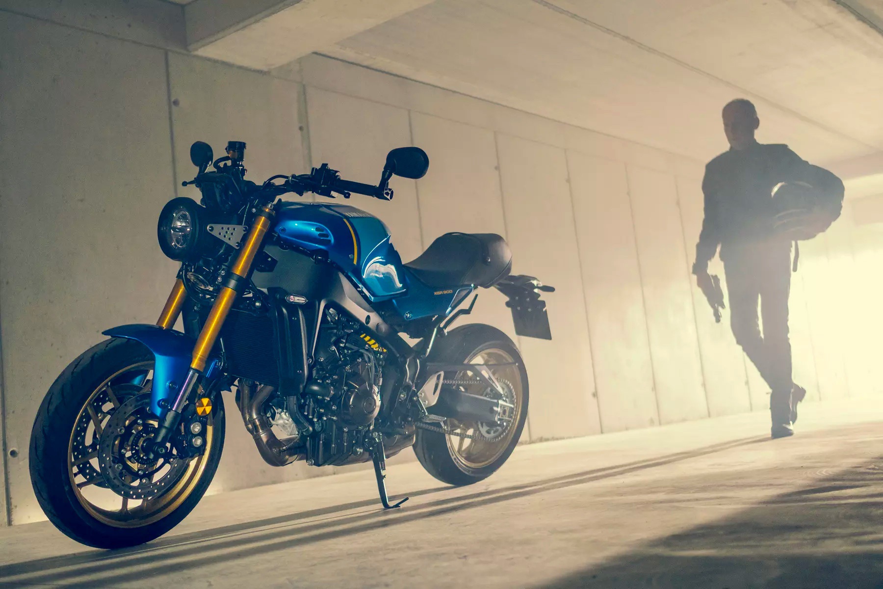 A man approaches the 2022 Yamaha XSR900 motorcycle - front 3/4 profile in a garage