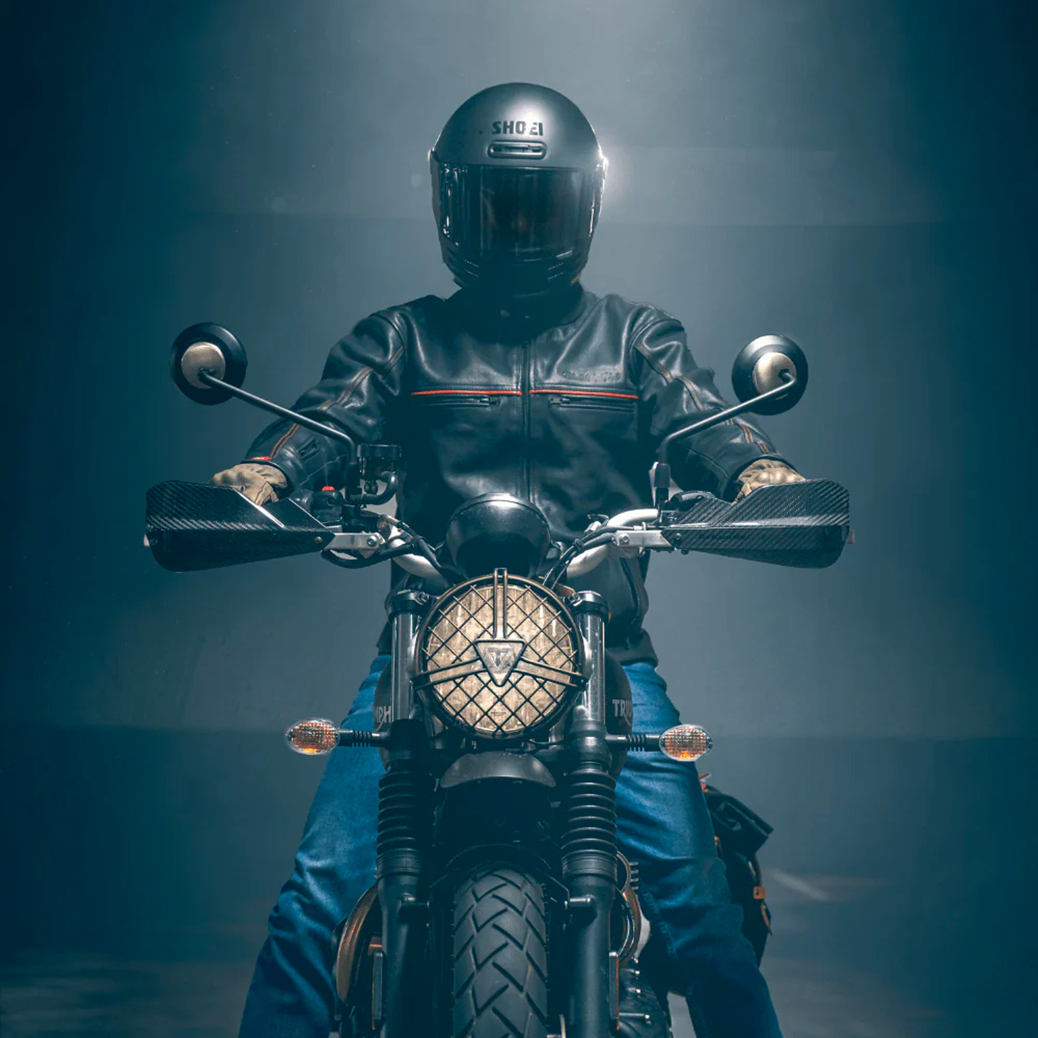Rider sits on a Triumph Scrambler motorcycle while wearing a Black Pup Moto Rumbler leather jacket